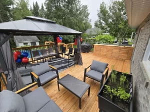 Terrasse en bois traité avec gazebo, mobilier extérieur et comptoir de cuisine pour barbecue