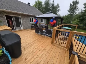 Terrasse en bois avec un gazebo décoré de ballons, mobilier extérieur et escalier sécurisé pour les enfants